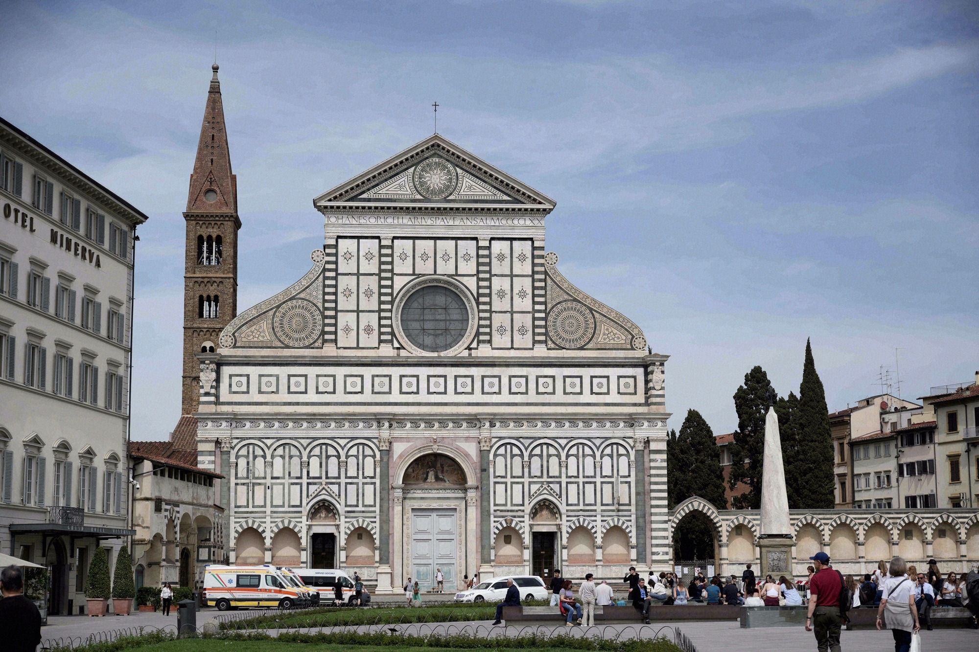 Die Fassade von Santa Maria Novella mit ihrer charakteristischen weiss-gruenen Marmorverkleidung, der Rosette und dem Glockenturm im Hintergrund.
