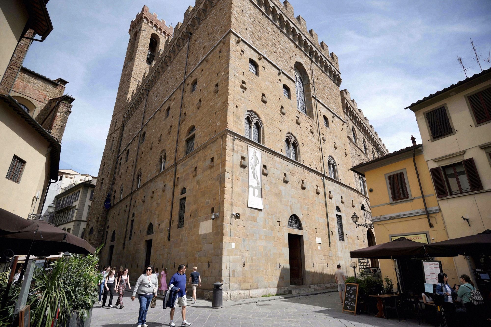 Die wuchtige Rustika-Fassade des Palazzo del Bargello aus naeher Perspektive, mit Touristen auf dem Platz davor.
