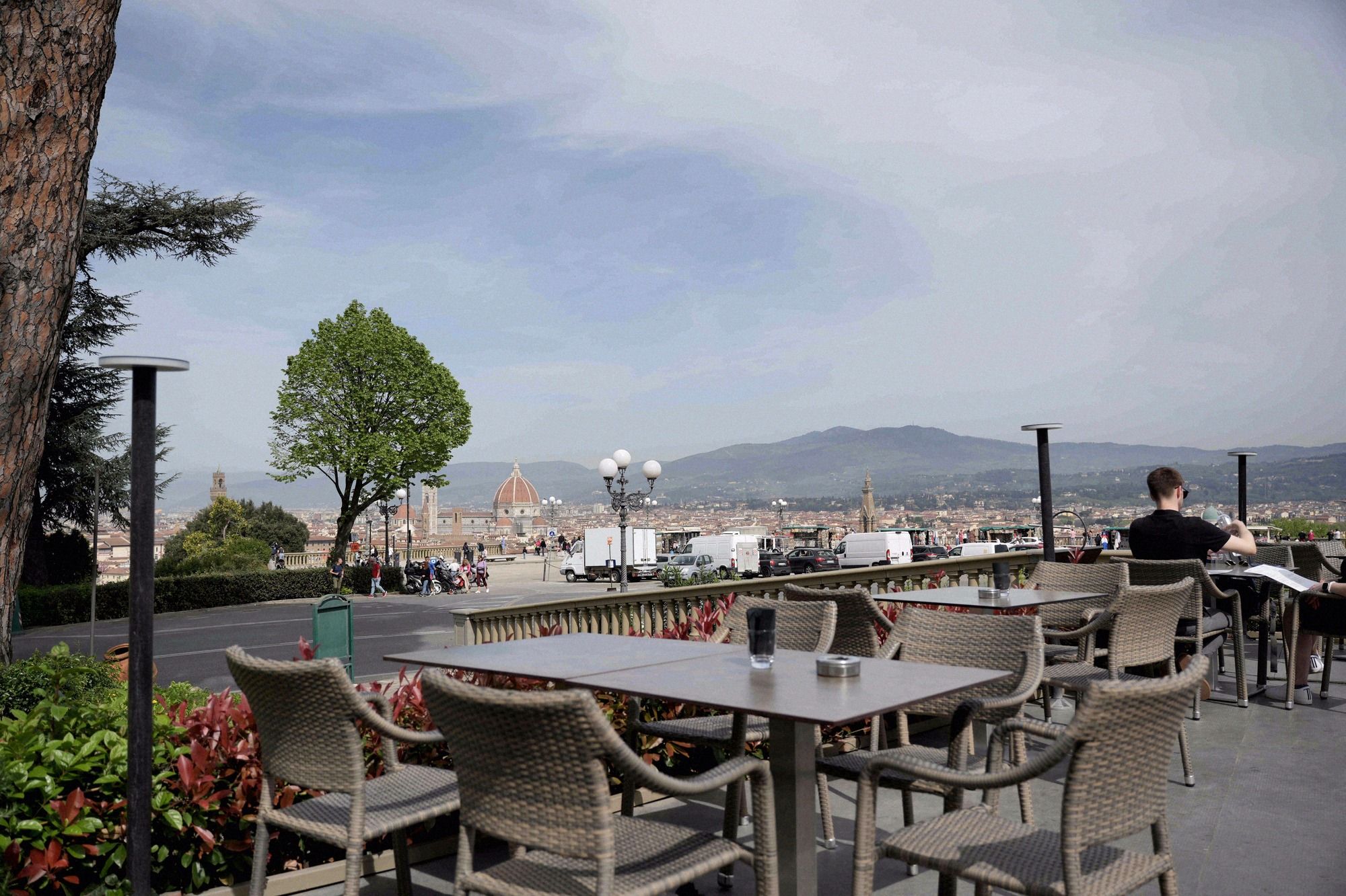 Terrassencafe auf dem Piazzale Michelangelo mit leeren Rattanstuehlen und Blick auf das Florenz-Panorama mit dem Dom.