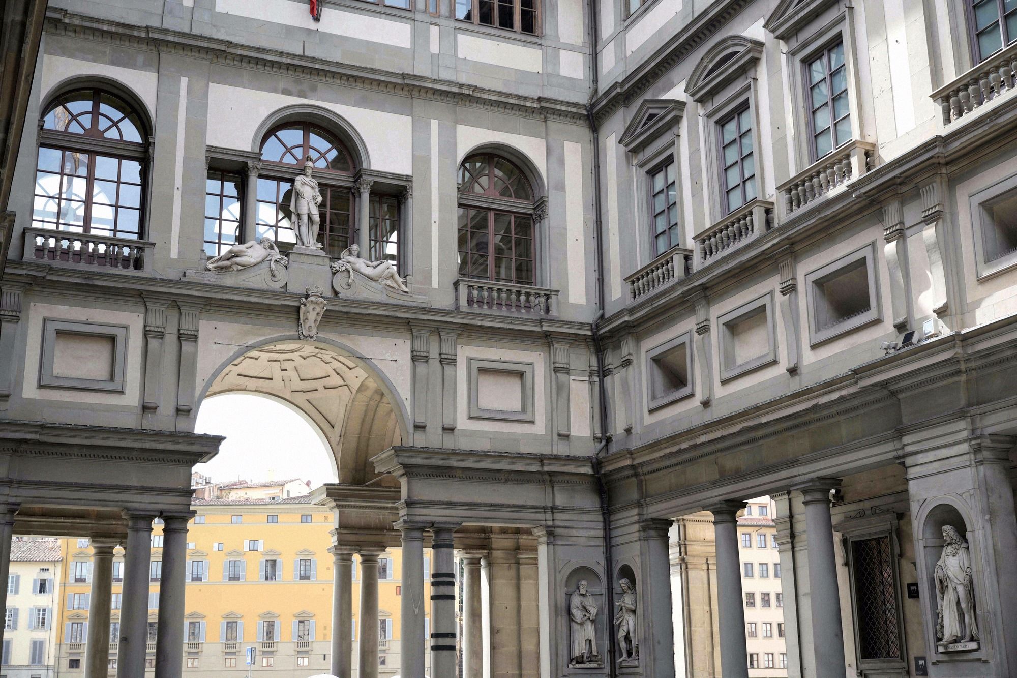 Der Innenhof der Uffizien mit den eleganten Saeulenboegen der Galeriefassade und dem Blick durch den Torbogen auf die gegenueberliegenden Renaissancehaeuser.